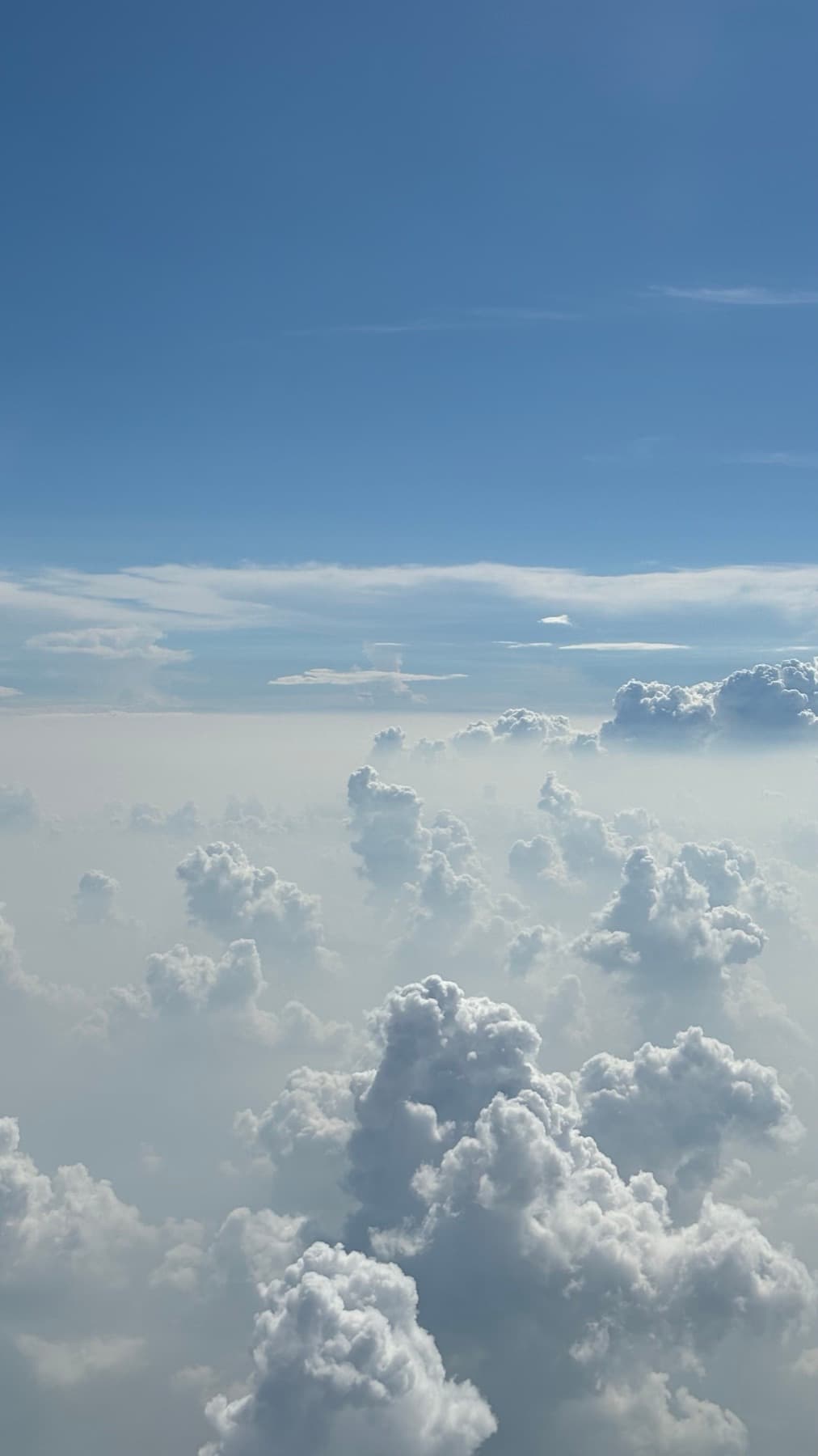 Cumulus towers rising through haze, seen from above.