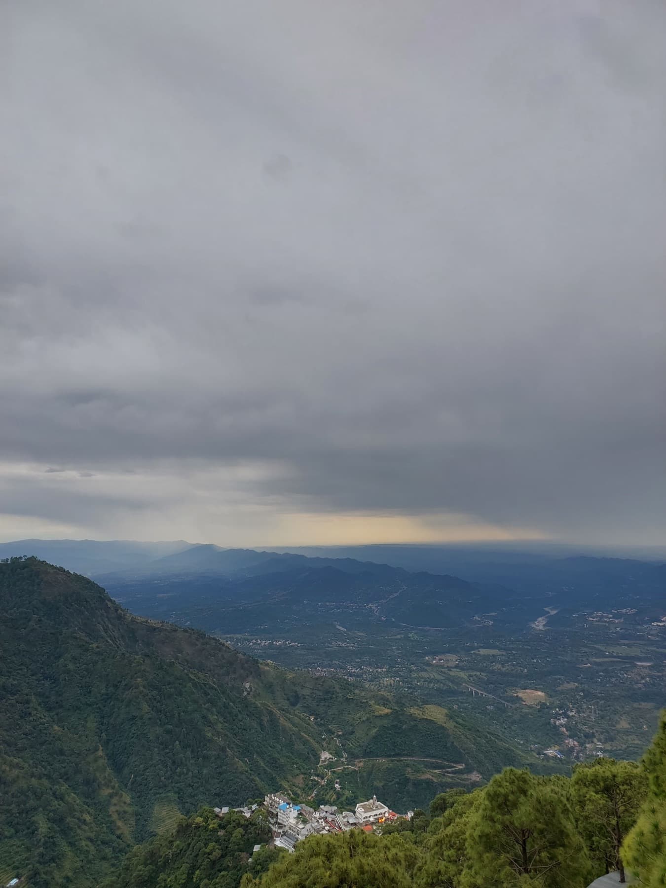 A hill town in a valley below, seen through breaking monsoon cloud.