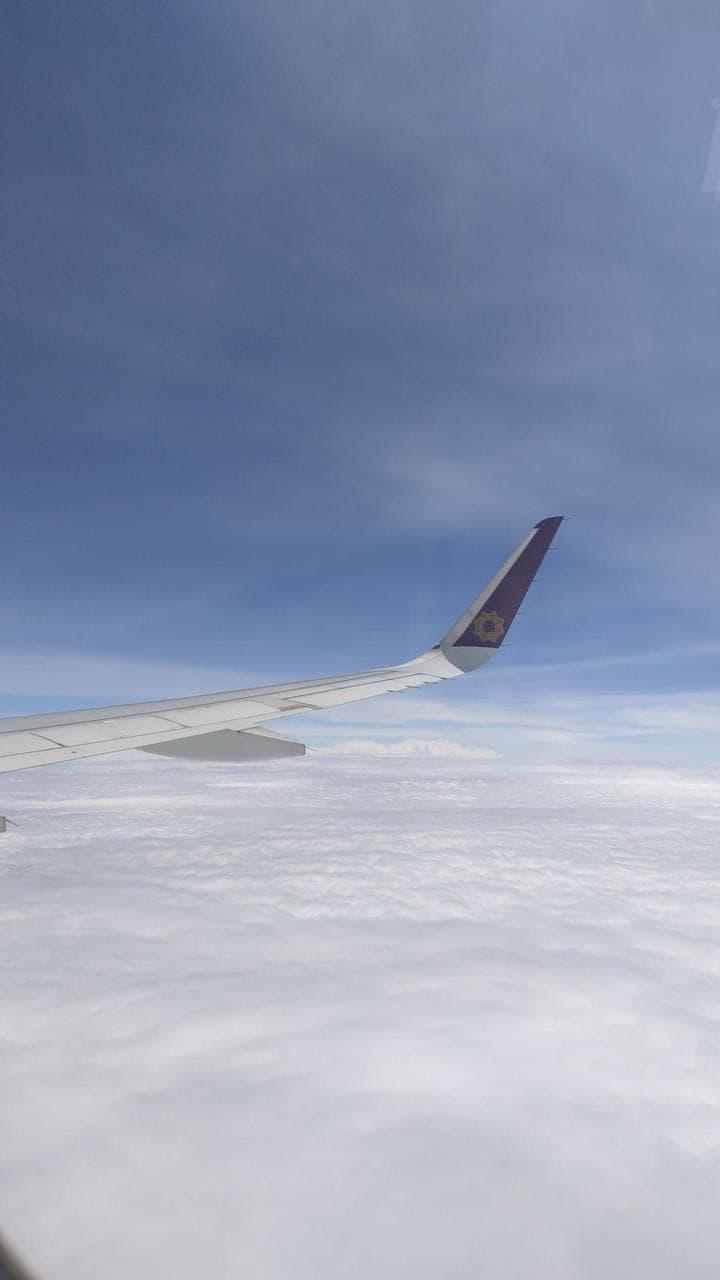 An aircraft wing above a flat deck of cloud in clear blue daylight.